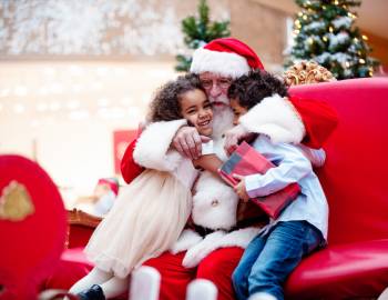 two young girls hugging Santa in a shopping mall