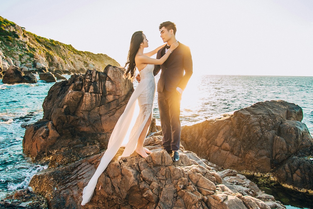 wedding photo of couple standing on lava rock in tropical setting