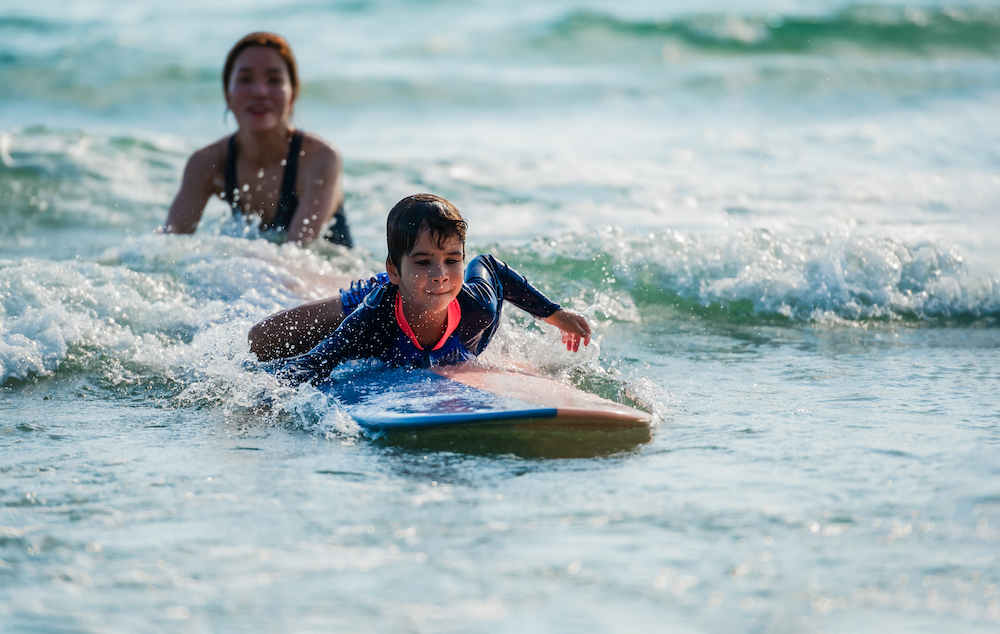 little kid learning to surf with instructor 