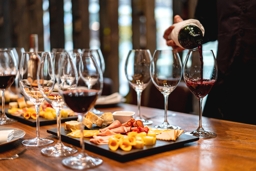 person pouring glasses of wine at a food and wine festival